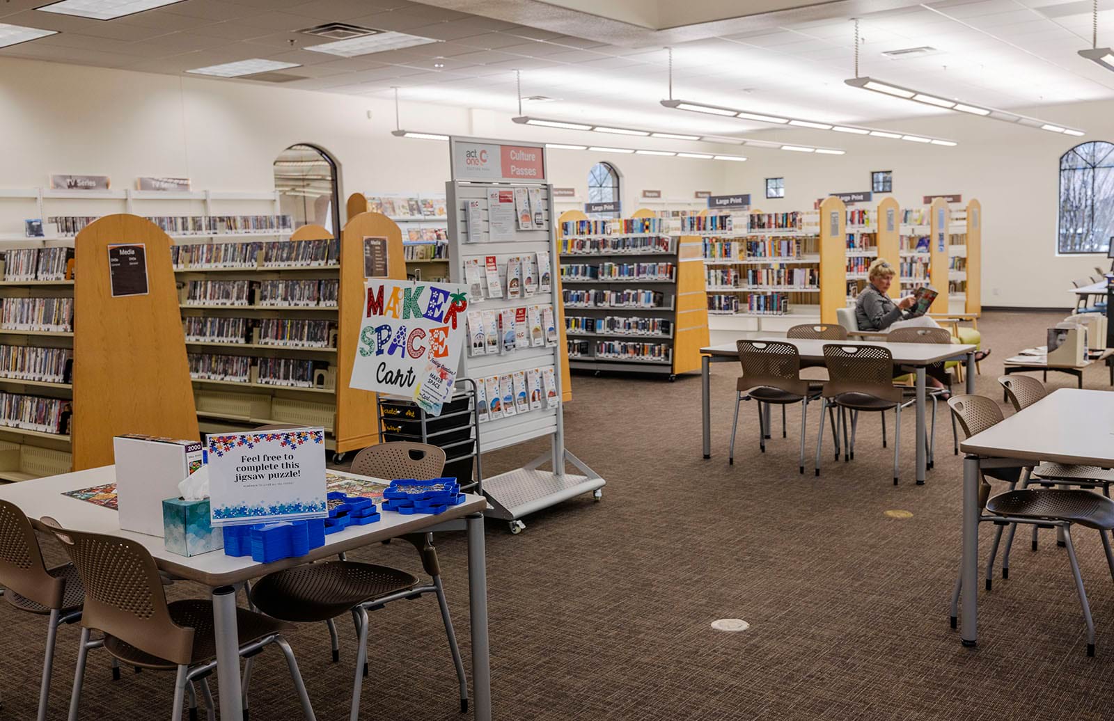 Photo of the puzzle table, makerspace cart and Culture Passes display