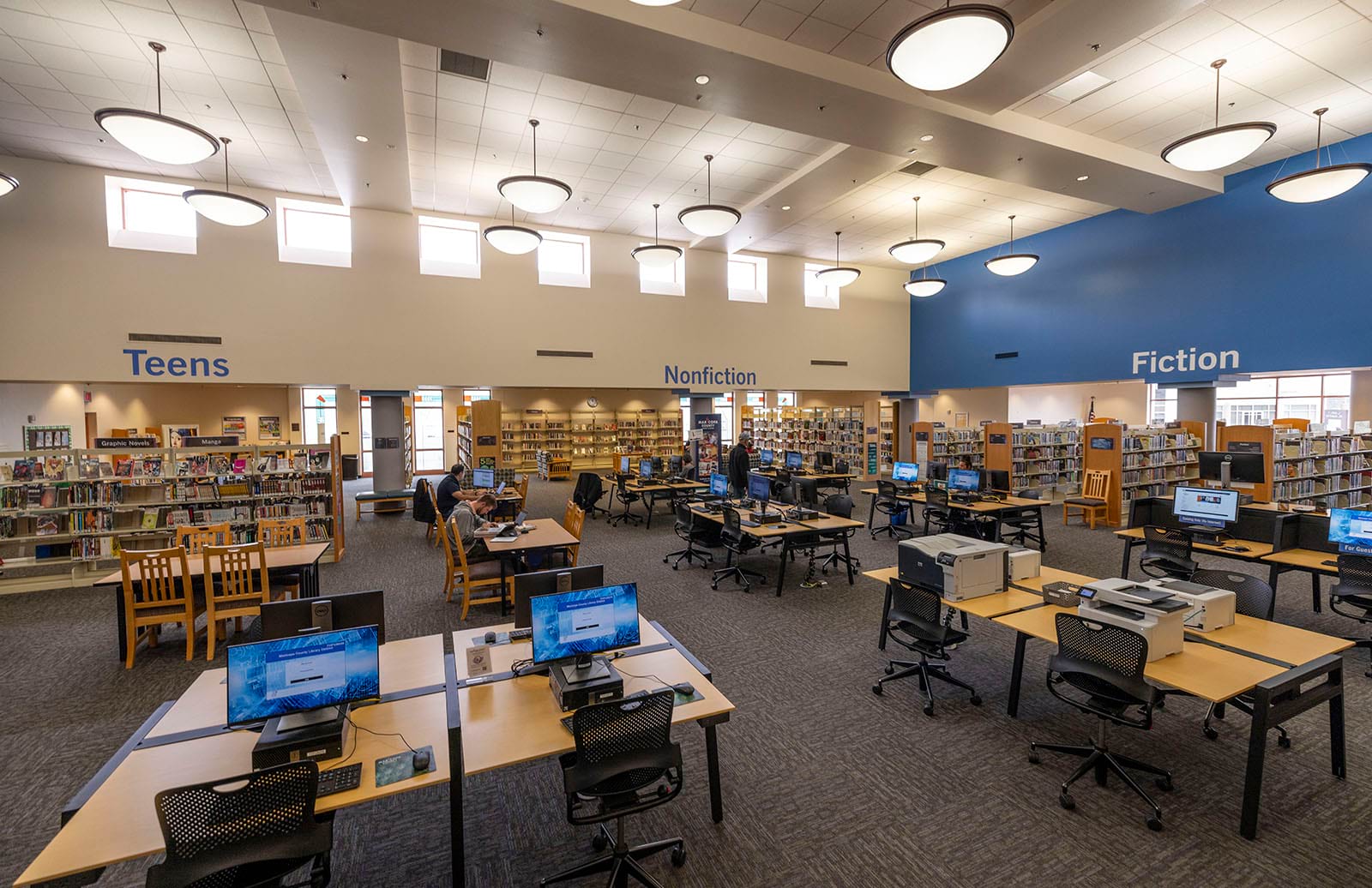 Photo of the computer area, tables, the teens section and Nonfiction section