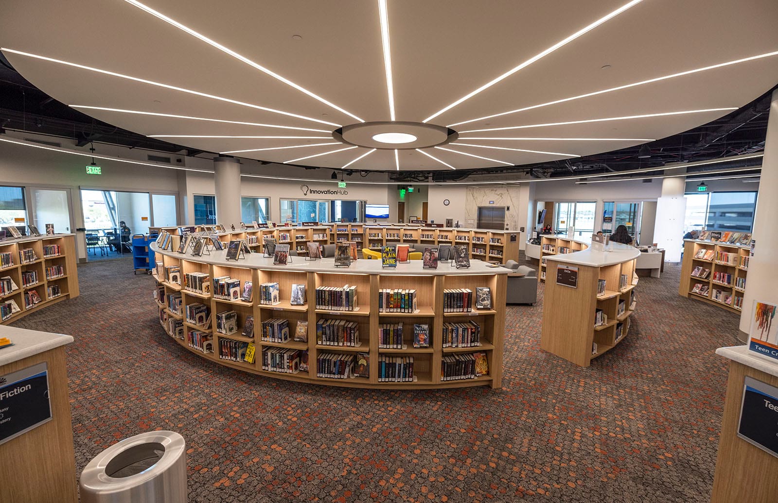 Photo of the 2nd floor teen shelves with study rooms and Innovation Hub in the background